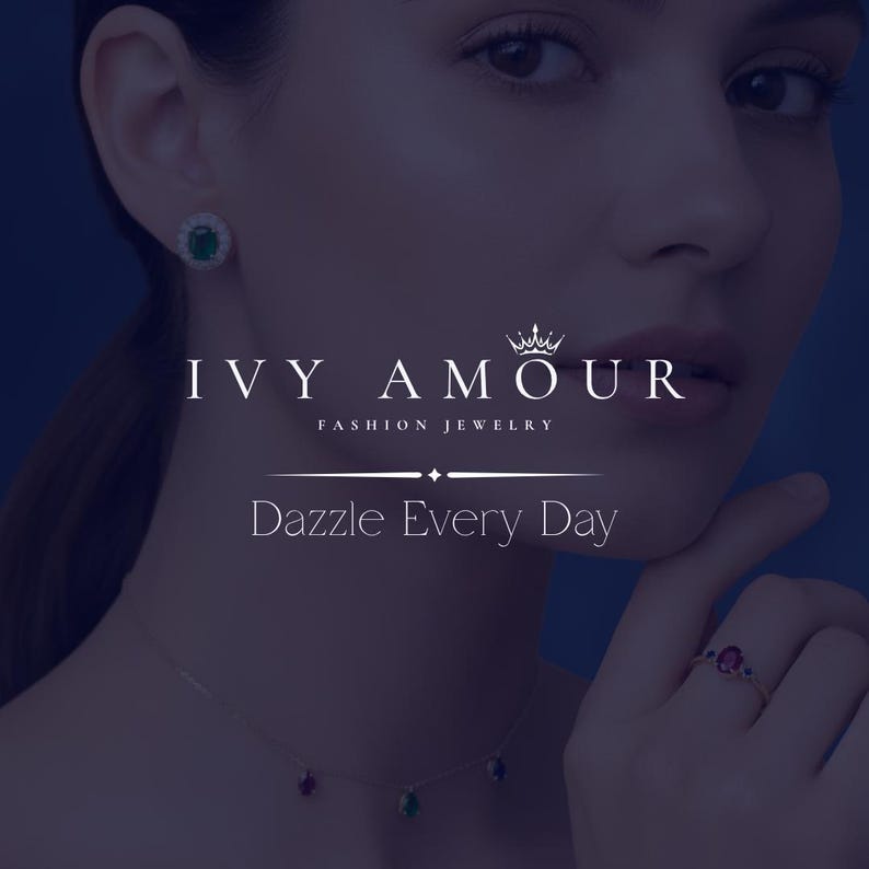 May include: A woman wearing fashion jewelry, including a necklace with three colored gemstones, a ring with a red gemstone, and a pair of emerald earrings. The image includes the text "IVY AMOUR" and "Dazzle Every Day".