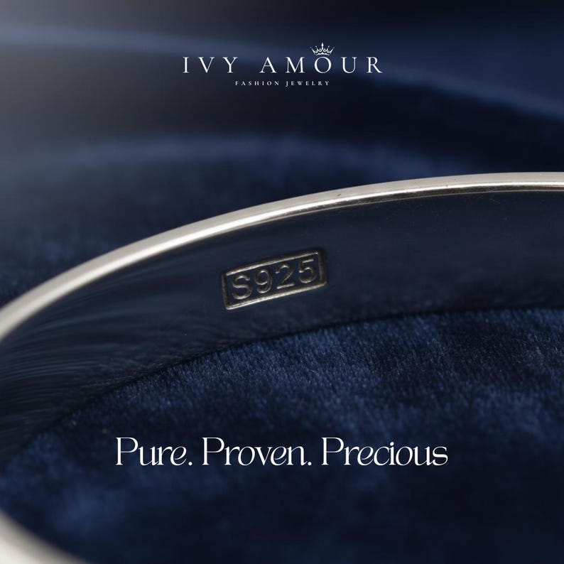 Puede incluir: Primer plano de una pulsera de plata con el sello "S925". La pulsera est&aacute; sobre un fondo azul oscuro. Tambi&eacute;n se ve el texto "IVY AMOUR FASHION JEWELRY" y "Pure. Proven. Precious".