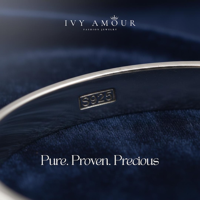 May include: Close-up of a silver bracelet with the stamp "S925". The bracelet is set against a dark blue background. The text "IVY AMOUR FASHION JEWELRY" and "Pure. Proven. Precious" are also visible.