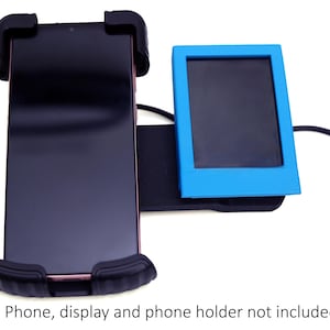 May include: A black phone holder with a black phone and a blue display. The phone holder has black rubber grips. The display is in a blue frame. A black cable with a green connector is attached.