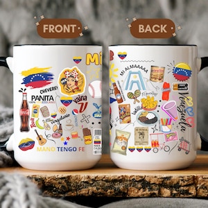 May include: A white ceramic mug with black handle and rim, featuring a colorful design with text and illustrations. The front side says "PANITA 100% VENEZOLANO" and "MANO TENGO FE". The back side says "VENEZUELA".