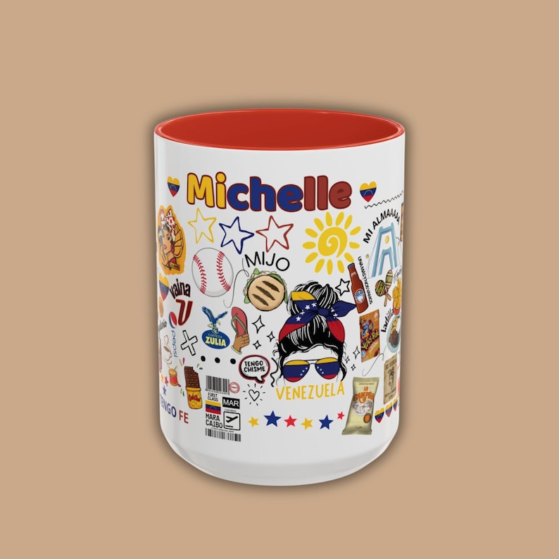 May include: A white ceramic mug with a red interior, featuring the name "Michelle" in red script. The mug is decorated with colorful Venezuelan-themed illustrations, including a baseball, sun, and the word "Venezuela".