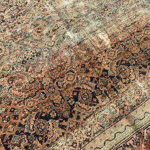 May include: An antique Persian rug with a detailed, faded floral pattern in shades of rust, navy, and beige. The rug's design features intricate medallions and borders, showcasing a vintage aesthetic.