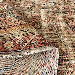 May include: A distressed, vintage-style rug with a detailed, repeating pattern. The rug features a color palette of muted reds, blues, and tans, with a fringed edge. The design has an aged, worn appearance, suggesting it is an antique or a reproduction.