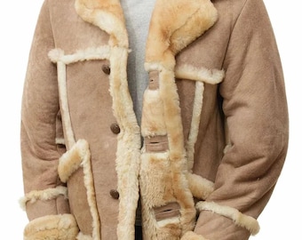 May include: A tan shearling coat with a light brown exterior and cream-colored shearling lining and trim. The coat features a wide collar, button closures, and shearling cuffs. The coat is displayed on a mannequin.