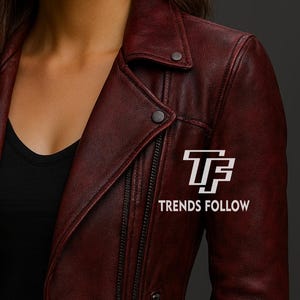 May include: A burgundy leather jacket with a classic biker style. Features a notched collar, asymmetrical zipper, and snap details. The text "TRENDS FOLLOW" is displayed on the jacket.