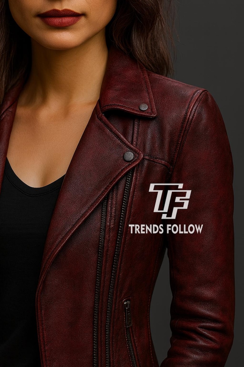 May include: A burgundy leather jacket with a classic biker style. Features a notched collar, asymmetrical zipper, and snap details. The text "TRENDS FOLLOW" is displayed on the jacket.