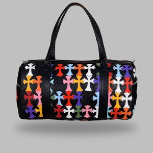 May include: Black duffel bag with a colorful cross pattern. The bag features a zipper closure, two handles, and a vibrant design of multi-colored crosses in red, orange, yellow, pink, blue, green, and white.