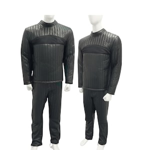 May include: Two black quilted sets of clothing displayed on mannequins. Each set includes a long-sleeved top with a high collar and vertical stitching, and matching pants. The top features a horizontal black panel across the chest.