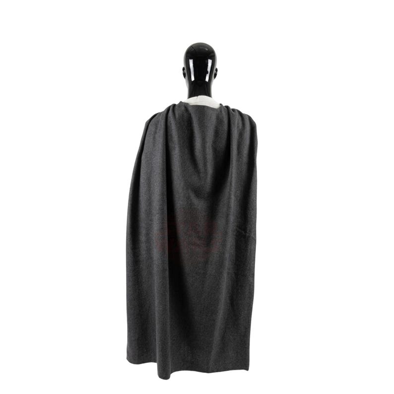 Puede incluir: Una capa gris oscuro drapeada sobre un maniqu&iacute; negro. La capa est&aacute; hecha de una tela suave y fluida y est&aacute; dise&ntilde;ada para ser usada sobre los hombros. El maniqu&iacute; est&aacute; sobre un fondo blanco.