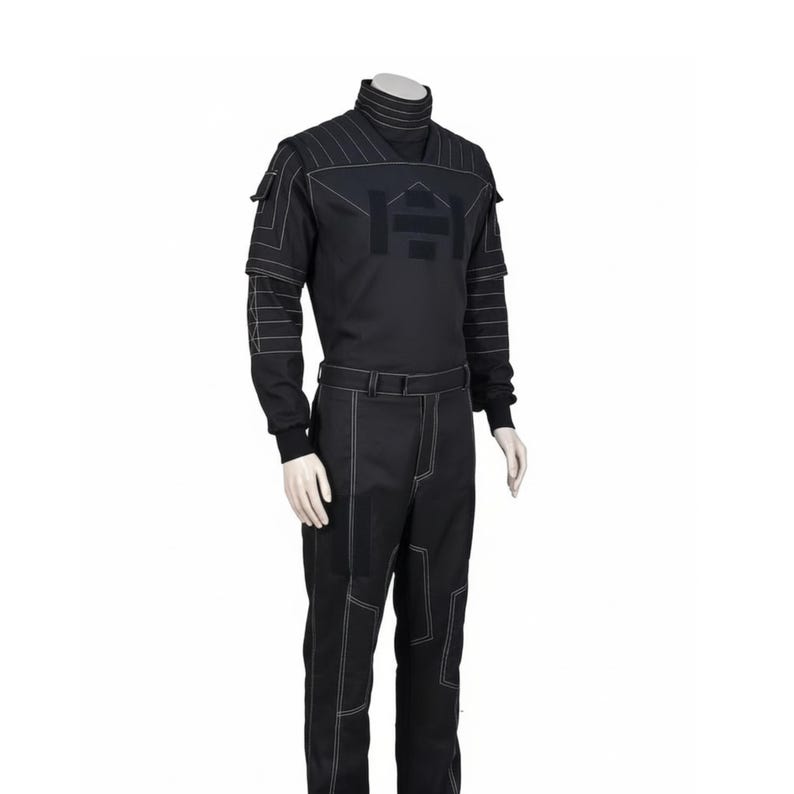 Pu&ograve; includere: Tuta nera con cuciture bianche. Presenta un collo alto, maniche lunghe e una cintura. Un design grafico &egrave; presente sul petto. I pantaloni hanno cuciture bianche.
