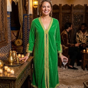 May include: A vibrant green velvet long-sleeved duster coat featuring a deep V-neckline and intricate gold embroidery along the front opening, cuffs, and hem. The garment has a straight silhouette and falls to the mid-calf, showcasing a soft texture.