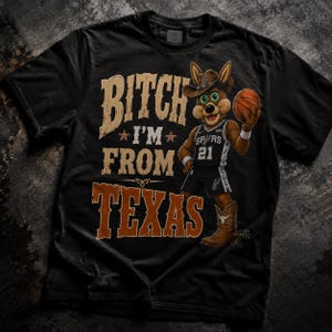 May include: Black t-shirt with a graphic featuring a cartoon coyote wearing a cowboy hat and basketball uniform, holding a basketball. Text on the shirt reads "Bitch I'm From Texas". The coyote is wearing cowboy boots.