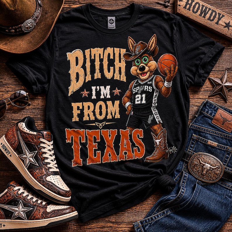 May include: Black t-shirt with the text "Bitch I'm From Texas" and a cartoon coyote wearing a cowboy hat and Spurs basketball uniform. The image includes a basketball, jeans, sneakers, and a cowboy hat.