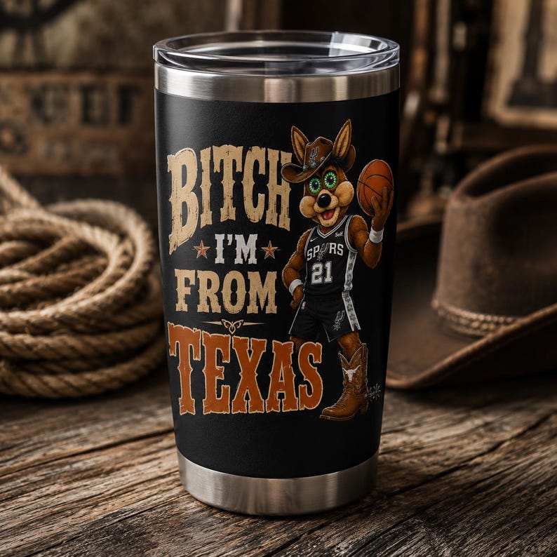 May include: Black stainless steel tumbler with the text "Bitch I'm From Texas" in tan and orange. A cartoon jackrabbit wearing a cowboy hat and Spurs jersey holds a basketball. The tumbler has a silver rim.