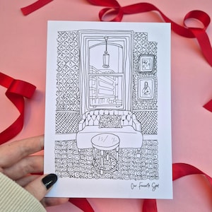 May include: Black and white line drawing of a room interior, featuring a window, sofa, and small table. The drawing includes the text "Our Favorite Spot" at the bottom right. Red ribbon decorates the pink background.