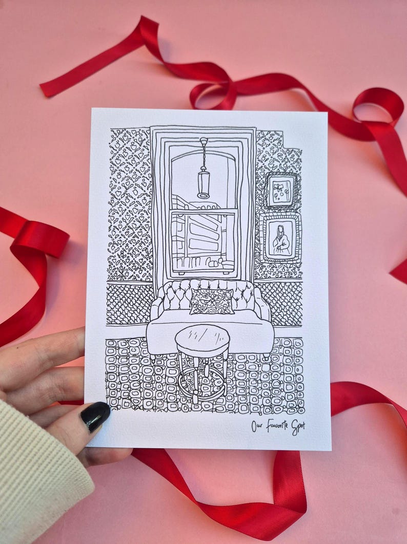 May include: Black and white line drawing of a room interior, featuring a window, sofa, and small table. The drawing includes the text "Our Favorite Spot" at the bottom right. Red ribbon decorates the pink background.