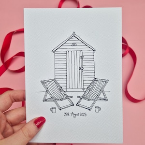 May include: Black and white line drawing of a beach scene. The illustration features a beach hut, two deck chairs, and two mugs. The date "29th August 2025" is written below the scene. The image is on a white card.