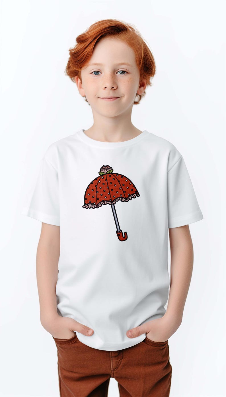 May include: White t-shirt featuring a cartoon umbrella design. The umbrella has a red polka-dot canopy, a silver handle, and a red curved handle. The shirt is worn by a child with red hair.