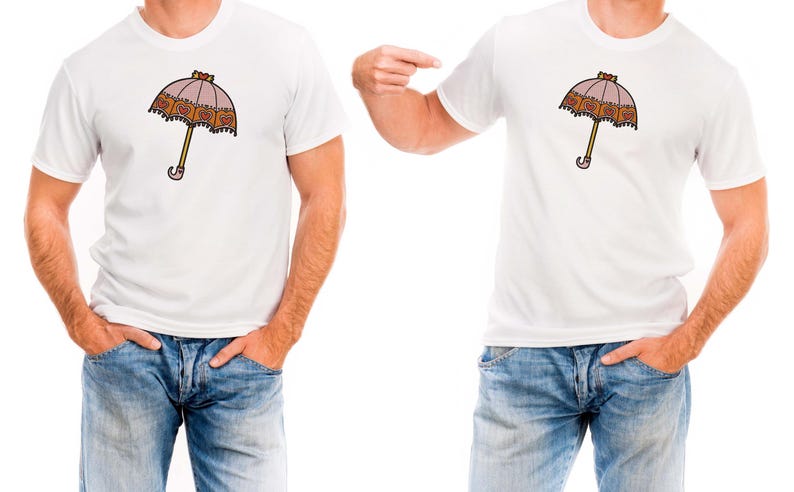 May include: White t-shirt featuring a cartoon umbrella design. The umbrella has a pink canopy with a decorative border, a yellow handle, and a curved handle end. The shirt is paired with blue jeans.