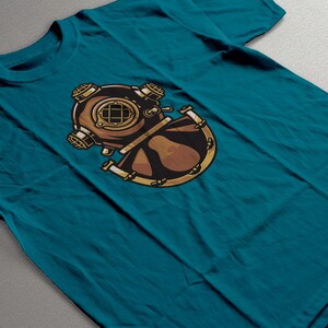 Peut inclure: T-shirt de couleur sarcelle avec un motif de casque de plong&eacute;e vintage. Le motif est marron et dor&eacute;, avec des d&eacute;tails complexes. Le t-shirt est en mati&egrave;re souple, adapt&eacute; au port d&eacute;contract&eacute;. Le motif est centr&eacute; sur le devant.