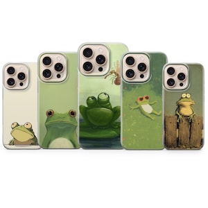 May include: Five phone cases with frog illustrations. Each case displays a unique frog design, such as a frog on a lily pad, a frog wearing sunglasses, and a frog on a wooden fence. The cases have a clear border. The illustrations are in a cartoon style.