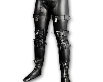 Pantalones de piel de vaca negra con correas, hebillas y anillos. Prenda de moda que marca tendencia.