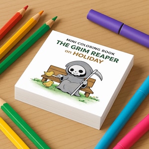 May include: A stack of mini coloring books with the title "The Grim Reaper on Holiday" featuring a cartoon Grim Reaper on a park bench. Colored pencils and markers in red, orange, yellow, green, blue, and pink surround the book.