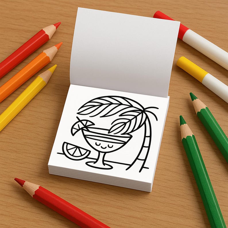 May include: A white notepad with a black line drawing of a cocktail with a palm tree and a lime wedge. Surrounding the notepad are red, orange, yellow, and green colored pencils and markers, all on a wooden surface.