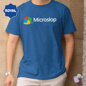 May include: Blue crew neck t-shirt with the word "Microslop" in white, above a colorful graphic. A "Royal" logo is in the upper left corner. The shirt is a solid blue color.