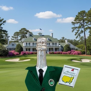 May include: A champagne bottle dressed in a green blazer, black tie, and holding a golf club and a Masters Tournament sign. The background features a golf course and a large white building under a blue sky.