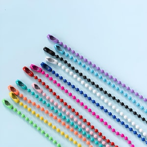 Peut inclure: Une collection de dix chaînes à billes de différentes couleurs, notamment violet, bleu clair, noir, blanc, bleu foncé, rouge, rose, sarcelle, orange, jaune et vert. Chaque chaîne comporte un connecteur métallique assorti à l'extrémité.