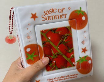 May include: A white photo binder featuring orange tomato graphics and the text "taste of Summer" and "I have a love affair with tomatoes I only had them in the summer." The cover includes a central window displaying a cluster of red tomatoes.