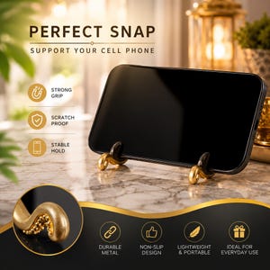 May include: A gold-colored metal cell phone stand featuring two octopus tentacle-shaped supports with textured suction cups. The stand holds a black smartphone horizontally. Text on the image includes PERFECT SNAP, SUPPORT YOUR CELL PHONE, STRONG GRIP, SCRATCH PROOF, STABLE HOLD, DURABLE METAL, NON-SLIP DESIGN, LIGHTWEIGHT & PORTABLE, and IDEAL FOR EVERYDAY USE.