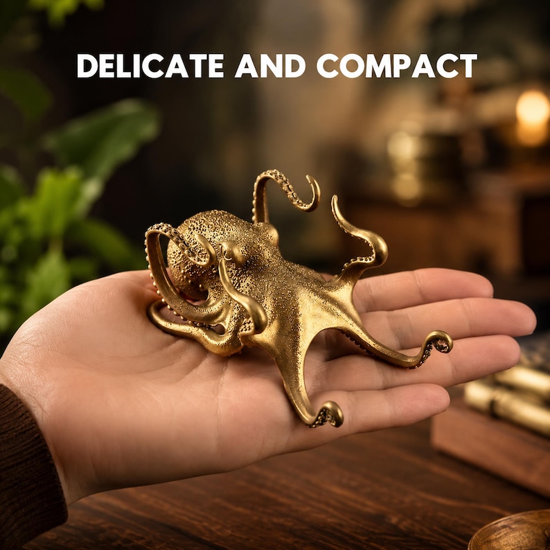 May include: A small, gold-colored metal octopus figurine with a textured surface and curved tentacles. The text DELICATE AND COMPACT is displayed above the object. The figurine is designed with intricate details on the head and limbs.