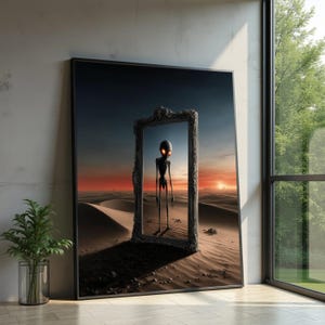 Op de afbeelding: Een ingelijste kunstdruk toont een alienfiguur in een woestijnlandschap, omlijst door een donkere, sierlijke rand. De alien heeft een slank postuur en gloeiende oranje ogen. De achtergrond toont een zonsondergang boven zandduinen.