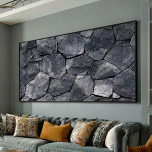 May include: A large rectangular wall art piece featuring a high-resolution print of dark gray, irregular-shaped stones fitted together in a tight masonry pattern. The artwork is framed in a thin black border and mounted on a light gray wall.