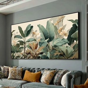 May include: A large framed botanical print depicting tropical plants in shades of green and brown, set against a cream backdrop. The artwork hangs above a grey sofa with patterned cushions, offering a calming, natural feel.
