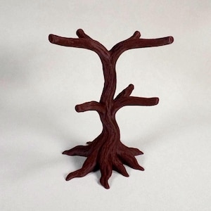 May include: A dark burgundy-colored jewelry display stand shaped like a tree. The stand has multiple branches for hanging earrings and necklaces. The base of the tree has a root-like design. The stand is approximately 10 inches tall.