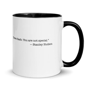 May include: White ceramic mug with a black interior and handle. The mug features the quote "News flash: You are not special." by Stanley Hudson in black text.