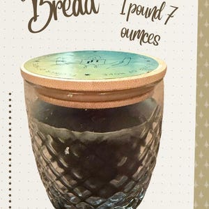 May include: A glass jar with a diamond-cut pattern and a light wood lid, labeled Banana Bread. The jar weighs 1 pound 7 ounces and measures 3.4 inches in height by 3.5 inches in width, as indicated by the text printed on the notebook page background.