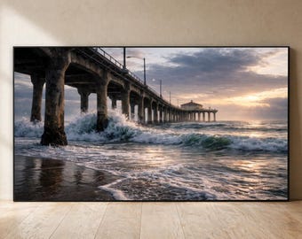 Puede incluir: Una impresión enmarcada de un muelle que se extiende hacia el océano. La imagen captura la estructura de hormigón del muelle, las olas rompiendo contra sus pilares y un cielo al atardecer. La paleta de colores incluye tonos de gris, marrón y dorado.