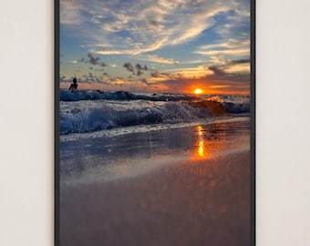 Puede incluir: Una impresión artística enmarcada que muestra una puesta de sol sobre el océano. La escena presenta olas rompiendo en una playa de arena con el sol bajo en el horizonte, proyectando un reflejo dorado sobre la arena mojada. Se ve una silueta.
