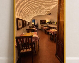 Puede incluir: Una impresión de arte mural enmarcada que representa el interior de un restaurante con un techo abovedado cubierto de luces. La escena presenta mesas de madera con manteles de cuadros rojos y blancos, sillas de madera oscura y suelos de terracota.