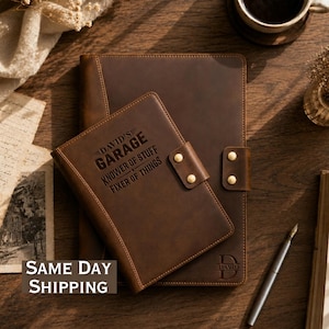 May include: A dark brown leather notebook cover and a smaller matching leather journal cover. The smaller cover features the engraved text DAVID'S GARAGE KNOWER OF STUFF FIXER OF THINGS and two brass snap buttons. The larger cover has a D monogram.