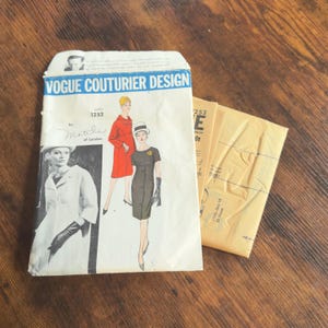 Puede incluir: Sobre de patrón de costura Vogue Couturier Design vintage con ilustraciones de moda femenina. El sobre presenta el texto "Vogue Couturier Design" y el número "1252". Se ven dos sobres de patrones adicionales.