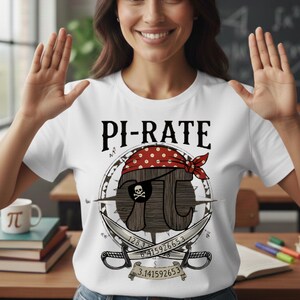 Peut inclure: T-shirt blanc avec le texte "PI-RATE" au-dessus d'un motif sur le thème des pirates. Le motif présente le symbole pi avec un cache-œil et un bandana rouge, des épées croisées et les chiffres de pi. Une tasse avec le symbole pi est visible.