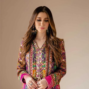 May include: A colorful, long-sleeved tunic with intricate embroidery in shades of purple, green, yellow, and pink. The tunic features a V-neck and a vibrant, patterned design. The sleeves have a bright pink cuff.