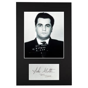 Peut inclure: Tirage encadré noir avec un portrait en noir et blanc d'un homme en costume et cravate, avec une plaque d'identification de la police. En dessous, une carte blanche avec une signature manuscrite "John Gotti".