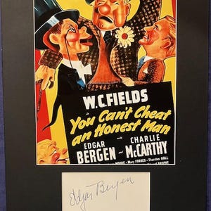 May include: A framed vintage movie poster for "You Can't Cheat an Honest Man" featuring W.C. Fields, Edgar Bergen, and Charlie McCarthy. The poster has a black background and includes an Edgar Bergen signature.